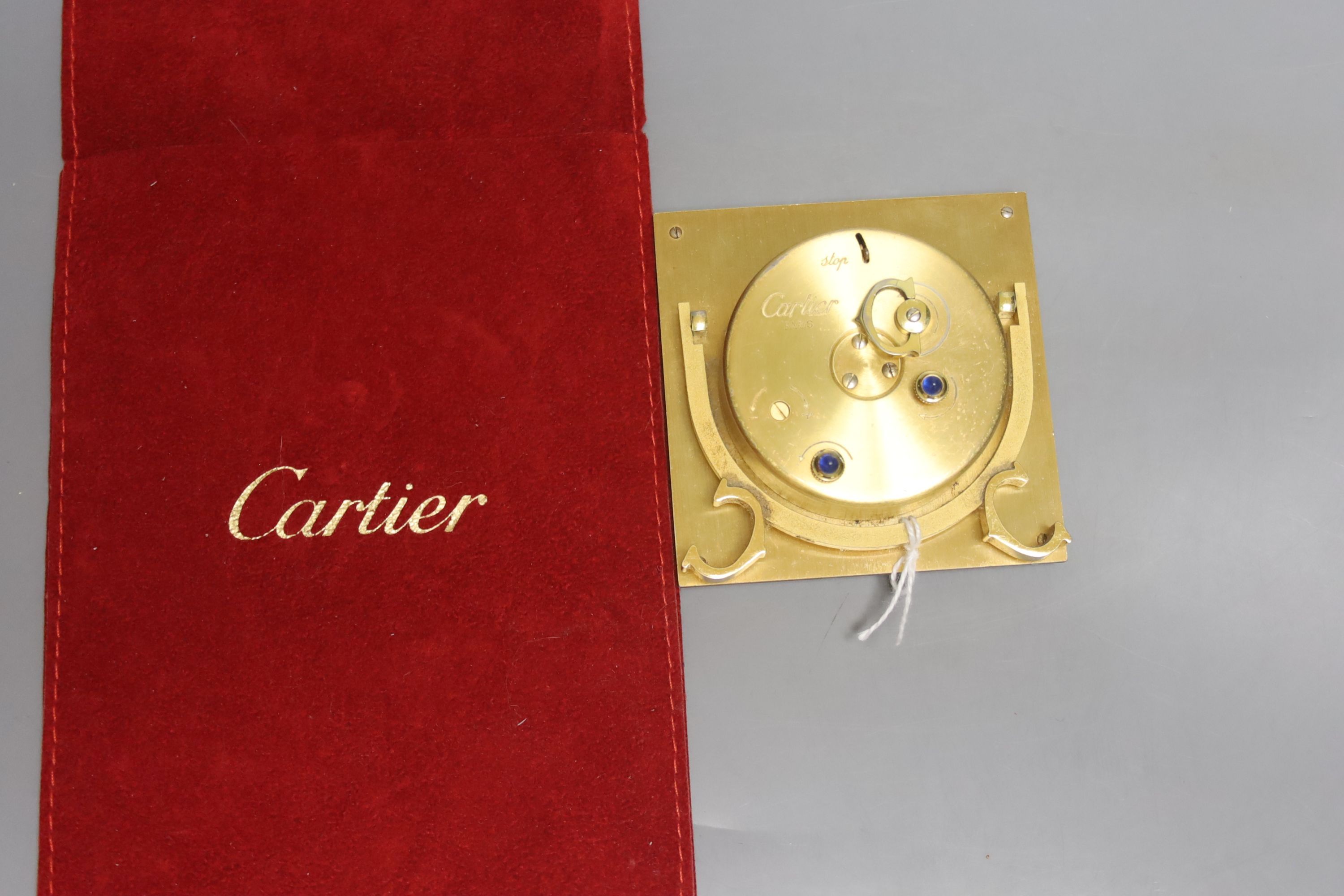 A gilt metal and faux tortoiseshell mounted Cartier travelling clock, with red Cartier pouch (small chips to border).